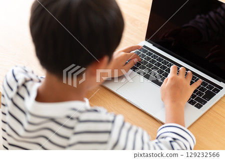 Elementary school boy using a computer at home Elementary school boy using a computer at home 129232566