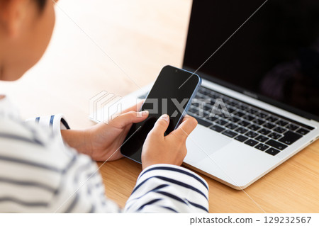 Elementary school boy looking at smartphone at home 129232567