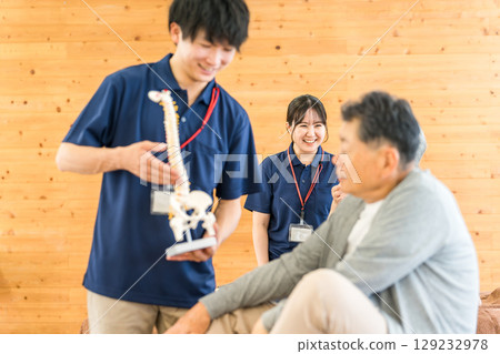 一名男性物理治療師（復健、運動矯形、訓練師）正在用骨骼標本向一位老年男性講解 129232978