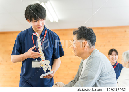 A male physical therapist (rehabilitation, sports orthopedics, trainer) explaining to a senior man using a skeletal specimen A male physical therapist (rehabilitation, sports orthopedics, trainer) explaining to a senior man using a skeletal specimen 129232982