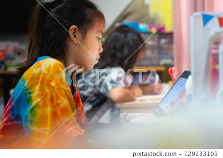 Two Asian schoolgirls studying at home, distance learning and education concept, doing homework together at desk. Two Asian schoolgirls studying at home, distance learning and education concept, doing homework together at desk. 129233101