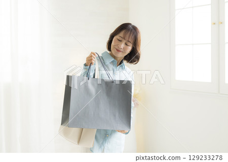 Woman handing over a shopping bag 129233278