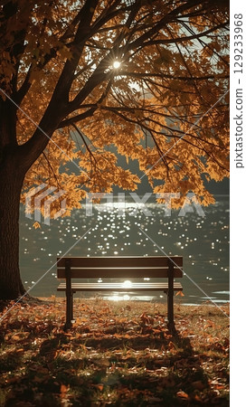 Swing hanging from tree branches over tranquil lake, surrounded by vibrant autumn foliage, capturing serene outdoor relaxation and natural beauty 129233968