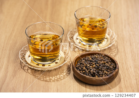 Glasses of barley tea and roasted barley grains on a wooden table Glasses of barley tea and roasted barley grains on a wooden table 129234407