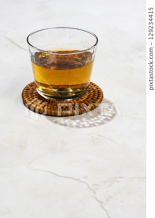 The shadow of a barley tea glass reflected on a white textured wall The shadow of a barley tea glass reflected on a white textured wall 129234415