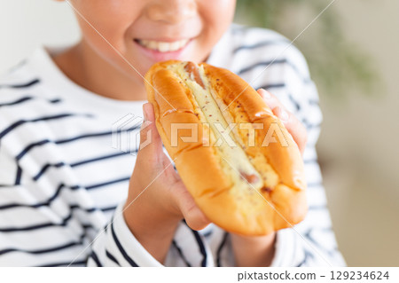 Elementary school boy eating a hot dog on a sandwich 129234624