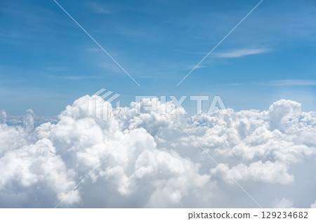 High nature view large white clouds on soft sky background. White clouds from the plane. White cumulus clouds on blue sky background, overcast skies, fluffy cloud texture sunny cloudscape, ozone layer 129234682