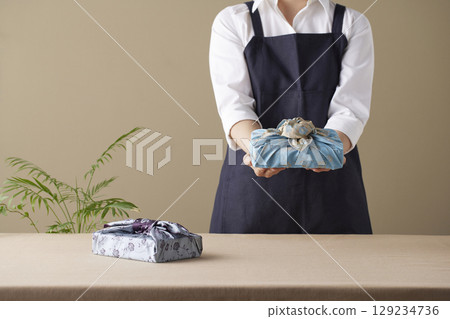 A woman wrapping a gift using bojagi (traditional Korean wrapping cloth). Reusable, handmade gift wrap for Korean holidays and anniversaries. 129234736