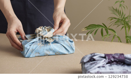 A woman wrapping a gift using bojagi (traditional Korean wrapping cloth). Reusable, handmade gift wrap for Korean holidays and anniversaries. 129234738