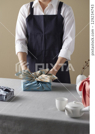 A woman wrapping a gift using bojagi (traditional Korean wrapping cloth). Reusable, handmade gift wrap for Korean holidays and anniversaries. 129234743