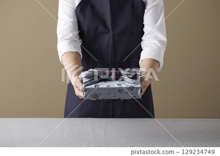 A woman wrapping a gift using bojagi (traditional Korean wrapping cloth). Reusable, handmade gift wrap for Korean holidays and anniversaries. 129234749