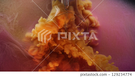 Broken lamp. Vapor paint. Defocused orange pink color fluid splash smoke cloud filling cracked glass in water on abstract background. 129234774