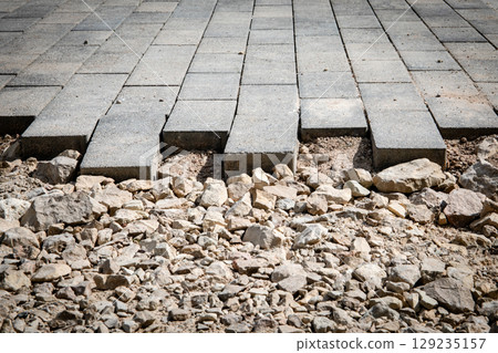 Unfinished Pavement with Exposed Rocks and Concrete Blocks Unfinished Pavement with Exposed Rocks and Concrete Blocks 129235157