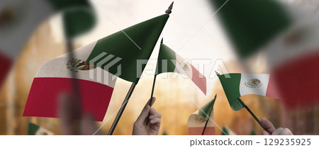 Mexico flags in their hands on a blurred urban background Mexico flags in their hands on a blurred urban background 129235925