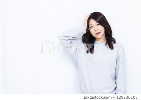 A surprised woman holding her head 129236103