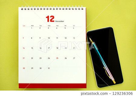 A work desktop with a calculator, calendar, and mobile phone A work desktop with a calculator, calendar, and mobile phone 129236306