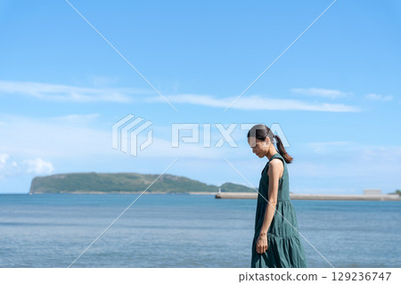 Young woman standing in the blue sea Young woman standing in the blue sea 129236747
