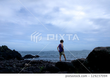 <Material> A boy walking alone in the rough sea in summer <Material> A boy walking alone in the rough sea in summer 129237094