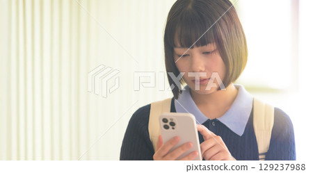 Female college student looking at smartphone 129237988
