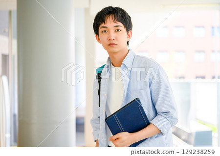 Male university student standing outside on campus 129238259