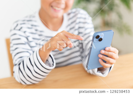 Elementary school boy looking at smartphone at home Elementary school boy looking at smartphone at home 129238453