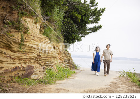 Back view of a couple walking along the coast 129238622