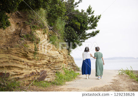 Back view of a woman walking along the coast 129238626