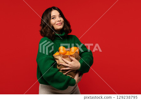 Woman in green sweater hugging bag full of ripe tangerines Woman in green sweater hugging bag full of ripe tangerines 129238795