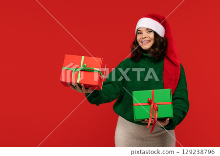 Smiling woman in Santa hat presenting Christmas gift boxes. Smiling woman in Santa hat presenting Christmas gift boxes. 129238796