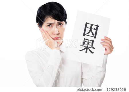 一名中年婦女手持寫著「因果」的紙，將手放在臉頰上，皺著眉頭 129238936