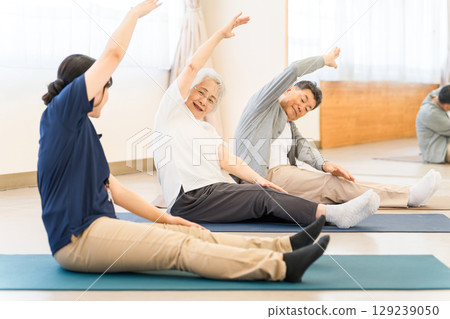 Rehabilitation at a care facility, welfare center, seniors stretching, elderly men and women with occupational therapists, caregivers, trainers 129239050