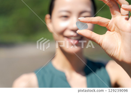 Woman picking up sea glass on the beach 129239096