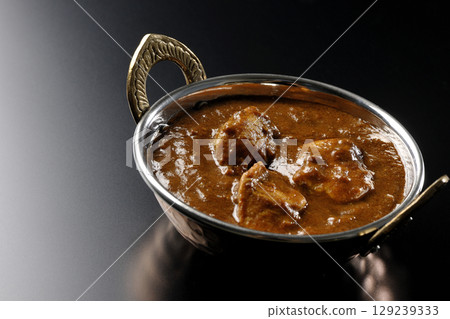Chicken masala curry photographed against a black background 129239333