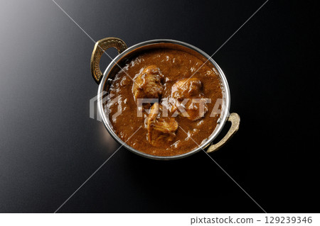 Chicken masala curry photographed against a black background 129239346
