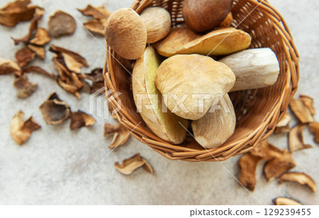 Fresh mushrooms overflowing a small wicker basket with dried mushrooms scattered around Fresh mushrooms overflowing a small wicker basket with dried mushrooms scattered around 129239455