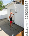 Teen Girl Shooting Basketball Into Hoop at Home 129239897