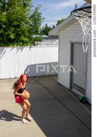 Teen Girl Preparing to Shoot Basketball Outdoors 129239900