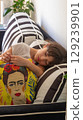 Young Girl Resting on Striped Couch Holding Frida Kahlo Pillow 129239901