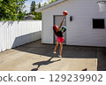 Teen Girl Playing Basketball in Driveway on a Sunny Day 129239902