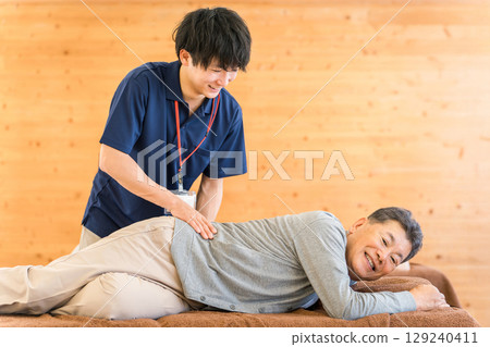 Male and female physical therapists and occupational therapists providing massage and stretching to elderly people as part of rehabilitation 129240411