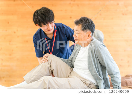 男性和女性物理治療師和職業治療師為老年人提供按摩和伸展運動作為復健的一部分 129240609