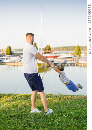 Father and Child Playing Together Near Boats on Grass Father and Child Playing Together Near Boats on Grass 129240658
