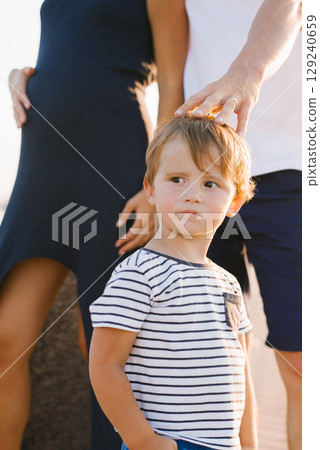 Young Boy Standing Near His Parents Outdoors Young Boy Standing Near His Parents Outdoors 129240659