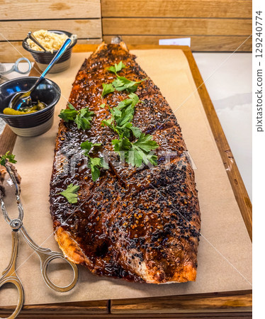 Close-up of a beautifully cooked salmon fillet with glaze and parsley garnish, served on parchment paper. Ideal image for culinary themes, food blogs, and restaurant menus. High quality photo 129240774