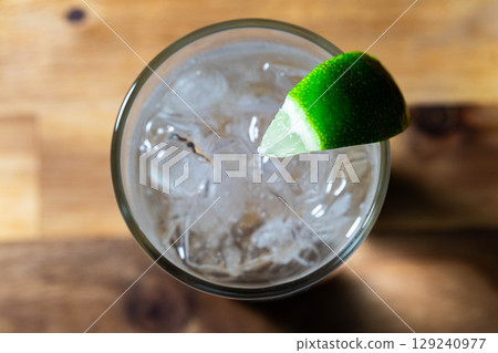[Cocktail ingredients] A delicious-looking gin and tonic poured into a glass with ice on a black background [Drink ingredients] 129240977
