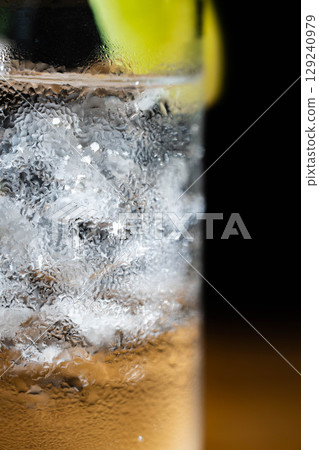 [雞尾酒配料] 在黑色背景下，將一杯美味的金湯力倒入加冰的玻璃杯中 [飲料配料] 129240979