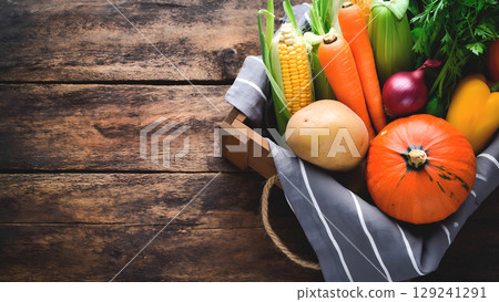 A wooden surface with a rustic texture, displaying a variety of fresh vegetables. 129241291
