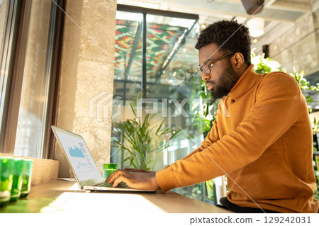 Entrepreneur man working from stylish workspace concentrating on virtual presentation 129242031