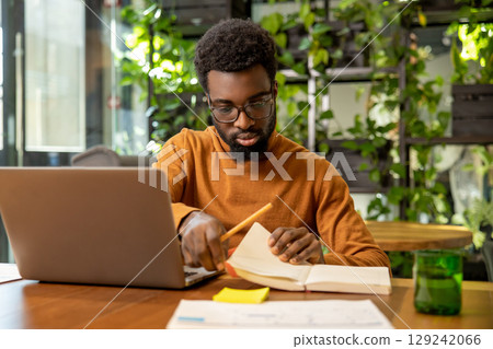 Man in glasses working on laptop reviewing digital reports 129242066