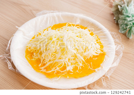 Add shredded cabbage to the eggs in the plastic wrap. Add shredded cabbage to the eggs in the plastic wrap. 129242741